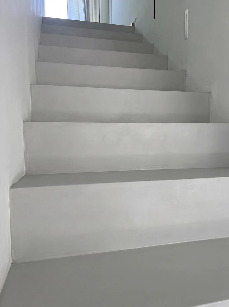 Fertig versiegelte Treppe aus Mikrozement nah von unten links, gleichmäßige Stufenfolge entlang der hellen Wand