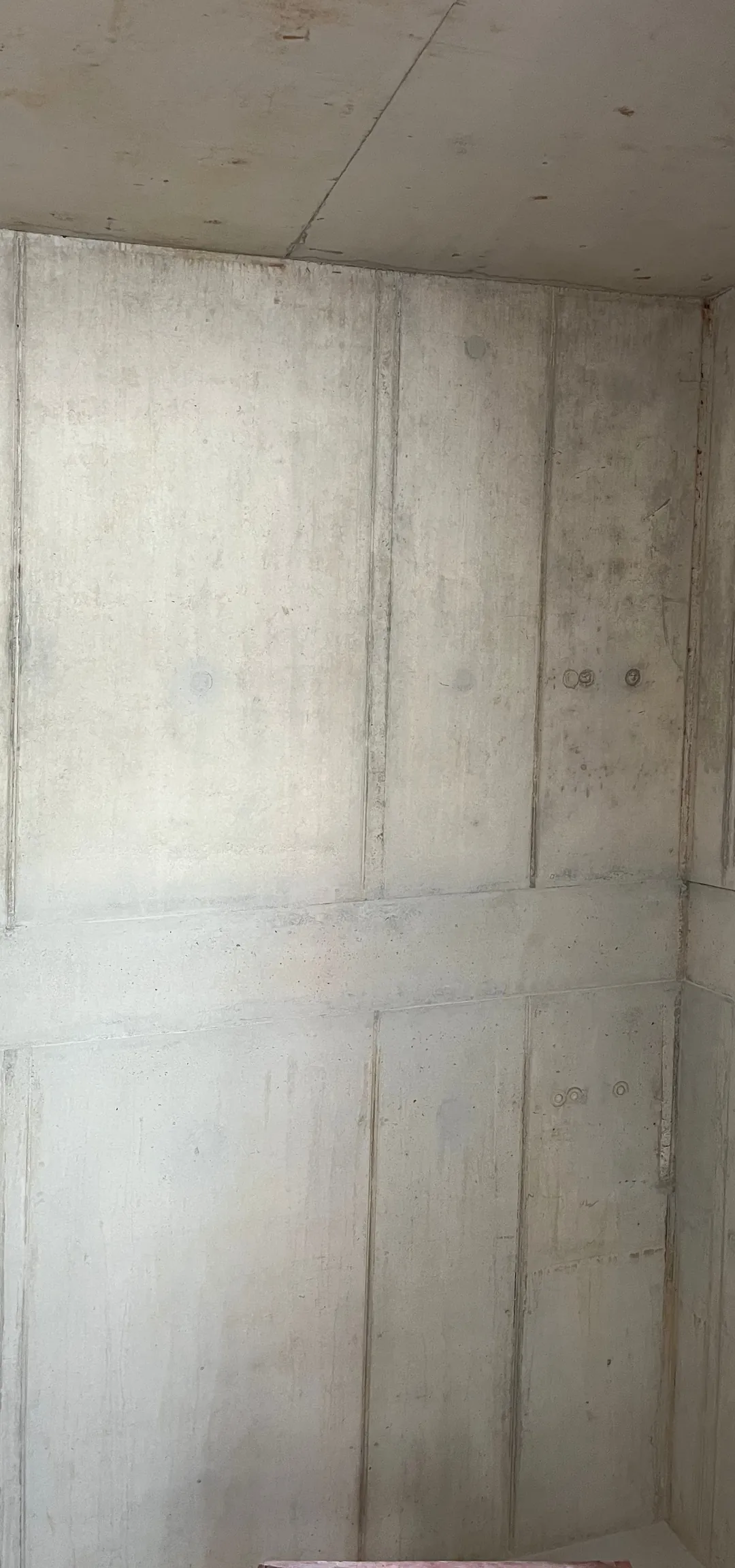 Dieselbe Sichtbetonwand nach Betonkosmetik und minimaler Retusche: Ankerkonen und Bohrlöcher geschlossen, ruhige Fläche mit sichtbarer Schalungsstruktur