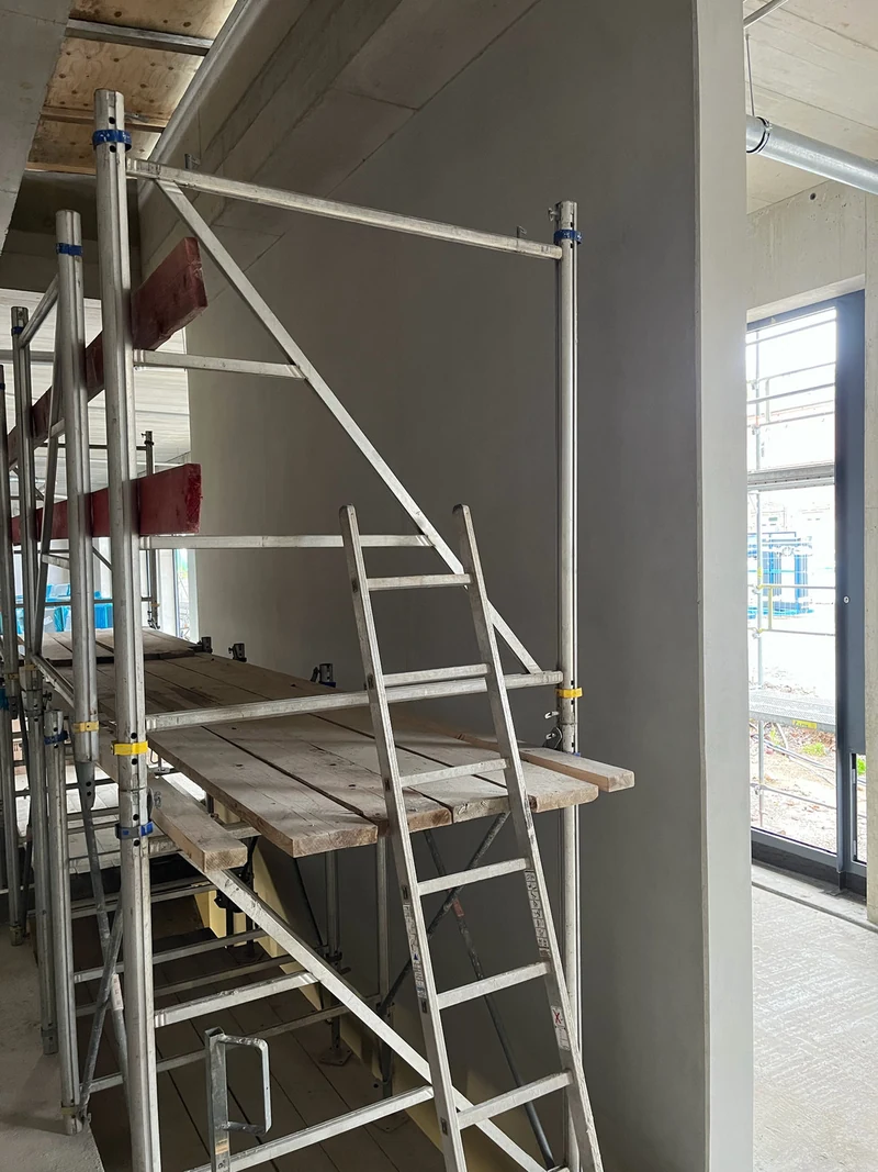 Fertig bearbeitete Betonfertigteil-Wandscheibe hinter einem Arbeitsgerüst