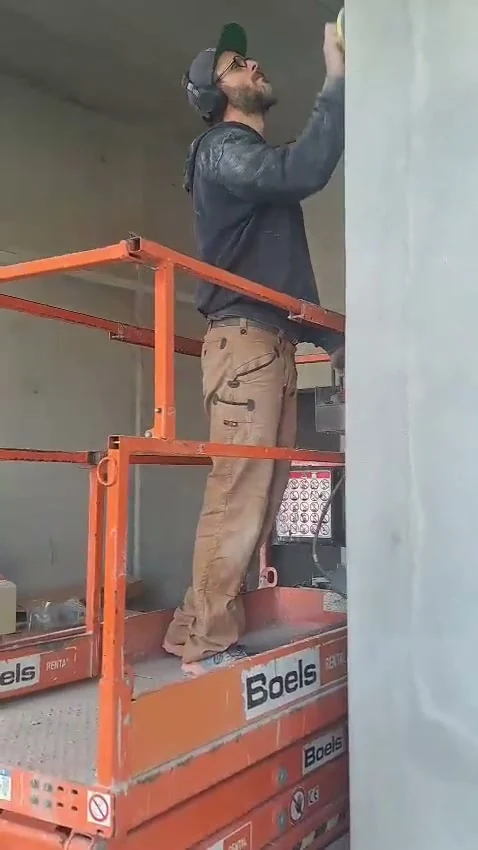 Video: Handwerker auf einer Hubbühne schleift eine Betonflanke nach dem Spachteln nach