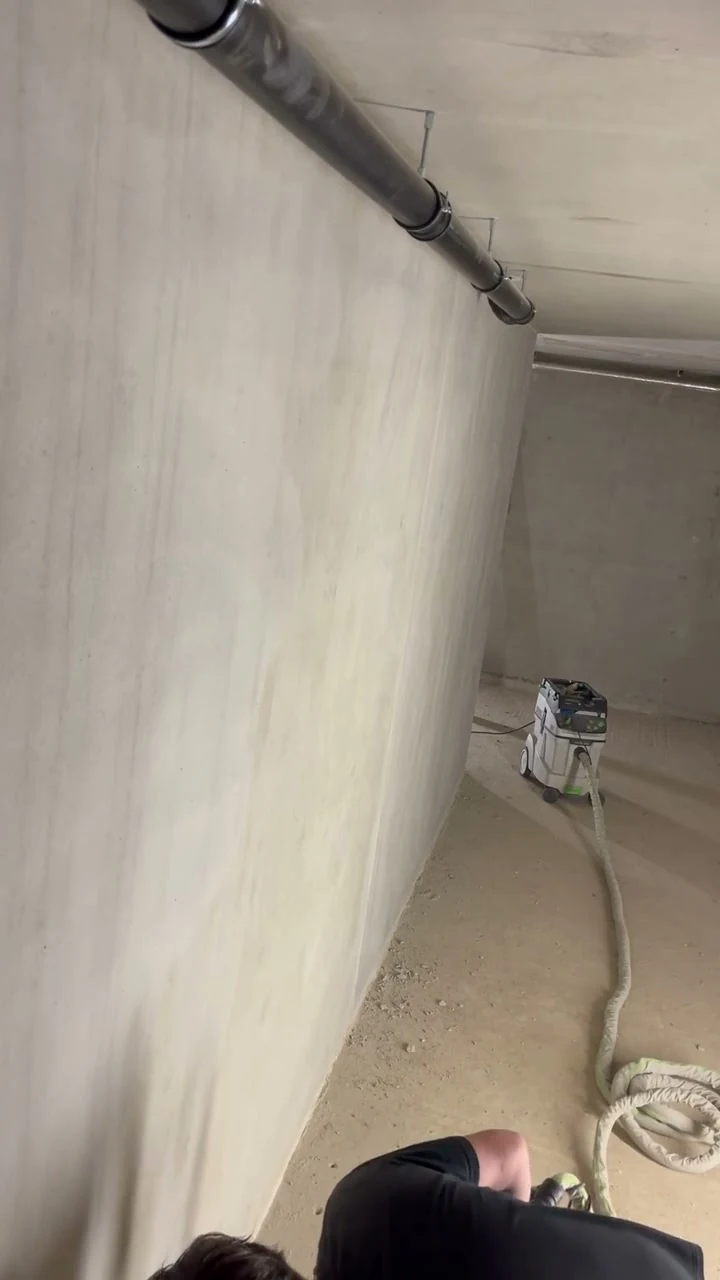 Video: Handwerker reinigt eine Betonfertigteilwand im Untergeschoss mit dem Langhalsschleifer