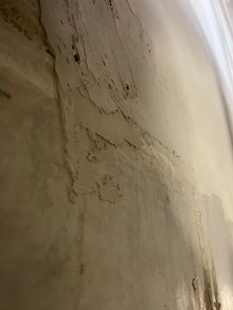 Nahaufnahme von grob verspachteltem Mörtel am Deckenspiegel einer Betonwand